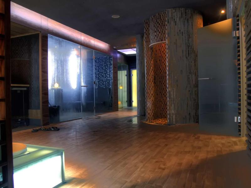 Moderner Raum mit Holz- und Glaswänden, warmem Licht und einem hohen, runden Säulenelement.