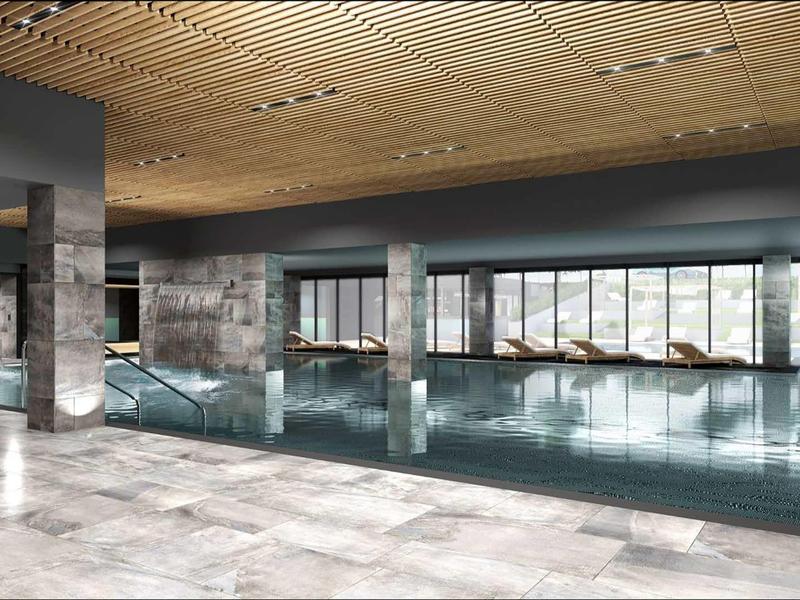 Großes, modernes Schwimmbad mit hellen Fliesen, Glasfenstern und Holzdecke.