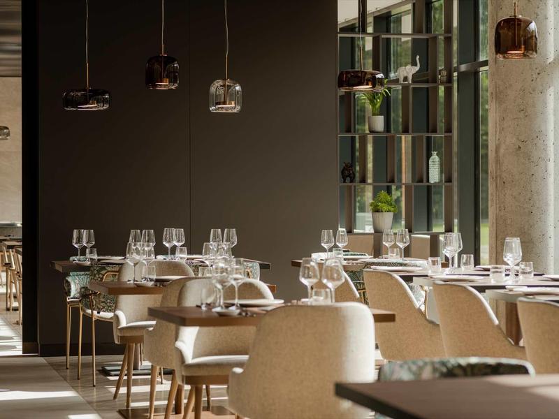 Modernes Restaurant mit hellen Polsterstühlen, gedeckten Tischen und großem Fenster für viel Tageslicht.