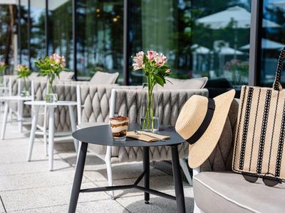 Moderne Terrasse mit Sitzmöbeln, Tischen, Blumen und Sonnenhut bei sonnigem Wetter
