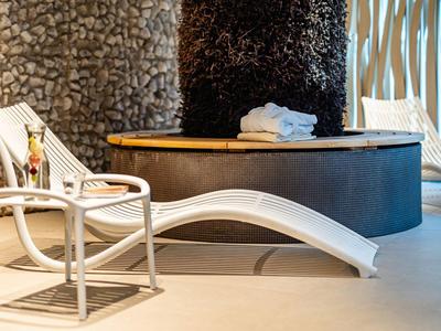 Moderne lounge met witte stoel en tafel naast ronde houten tafel en stenen muur.