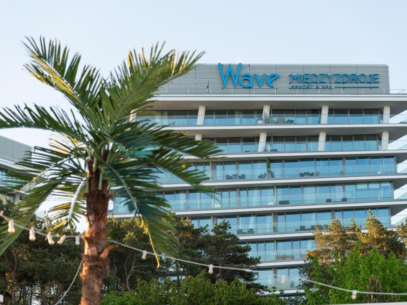 Modern hotelcomplex met glazen gevel en palmboom op de voorgrond onder een heldere hemel