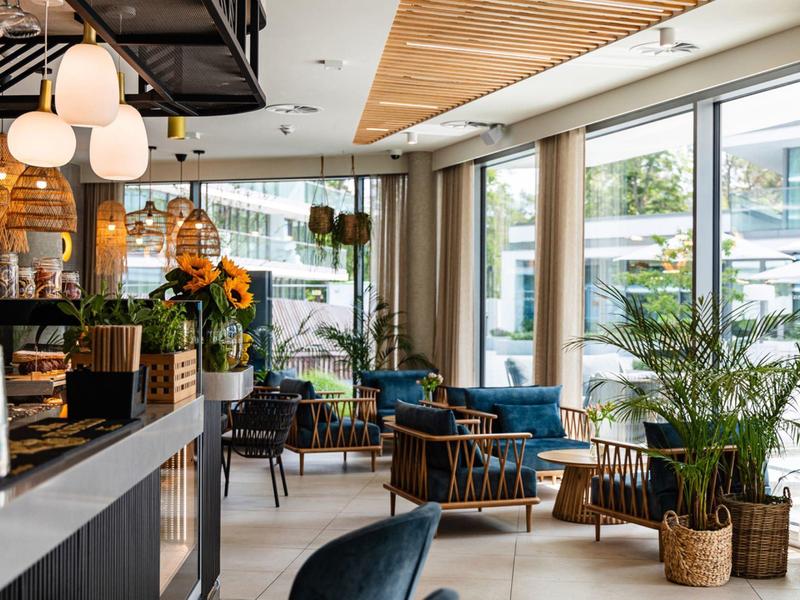 Modern ingerichte hotel lounge met grote ramen en groene planten.