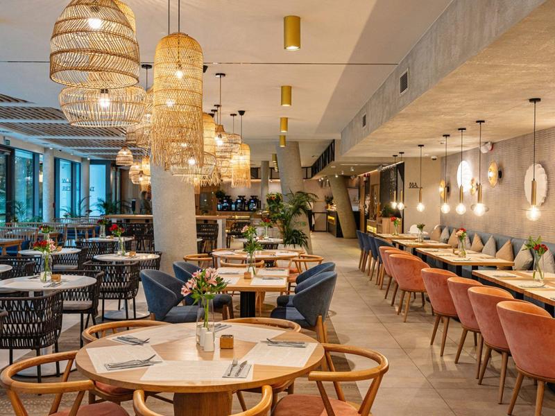 Modern restaurant met elegant interieur, ronde tafels en warme verlichting.