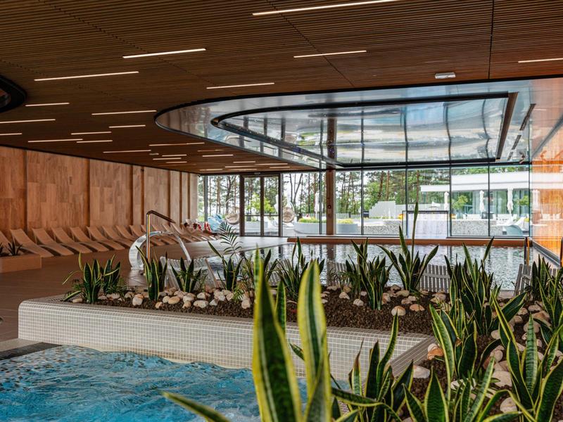 Moderne hotelhal met jacuzzi, planten en grote glazen ramen.