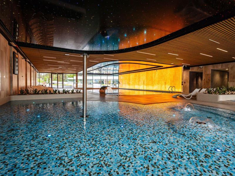 Modern overdekt zwembad met blauwe mozaïekvloer en grote ramen in een hotel