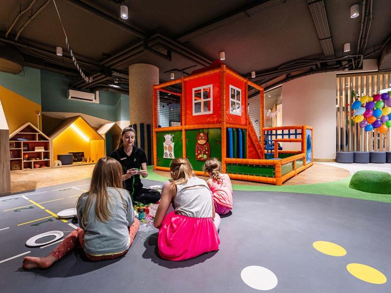 Kinderen zitten op de vloer van een kleurrijke binnenspeeltuin in een hotel