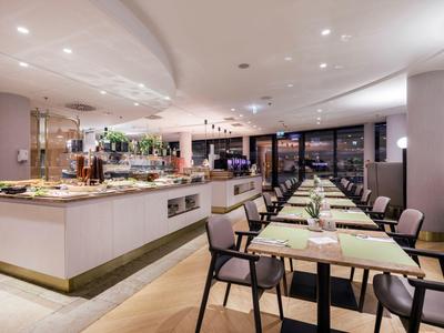 Modernes Restaurant mit elegant gedeckten Tischen und Buffetbereich in warmem Licht.