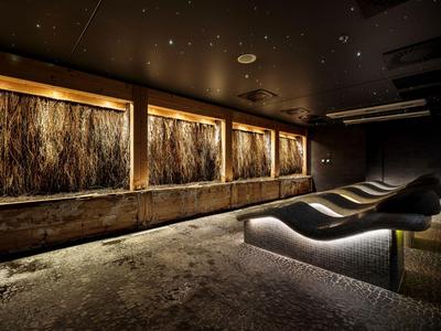 Dunkler Ruheraum mit beleuchteten Liegen und dekorativer Wandbeleuchtung.