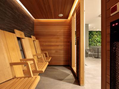 Moderner Warteraum mit Holzbänken und warmen LED-Lichtern neben einem Aufzug.