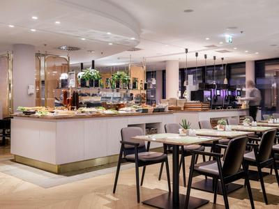 Modernes, helles Restaurant mit Buffetanlage und gedeckten Tischen in stilvollem Ambiente.