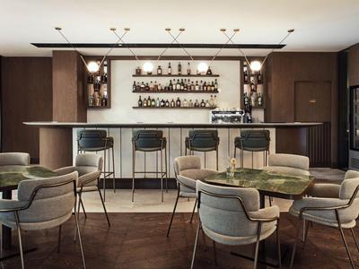 Moderner Hotelbarbereich mit Holzmöbeln und Barhockern in warmen Erdtönen.