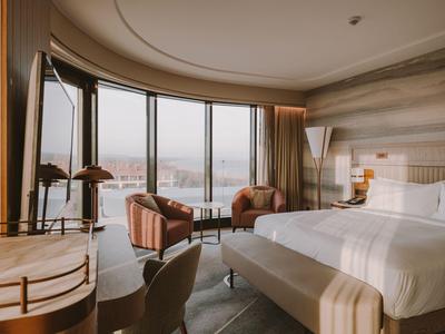 Modernes Hotelzimmer mit großem Rundfenster und Blick auf die Stadt.