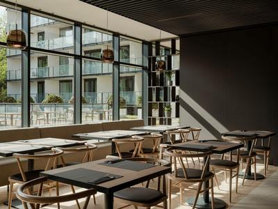 Modernes, helles Café mit Holzstühlen und großen Fenstern mit Blick auf eine Straße.