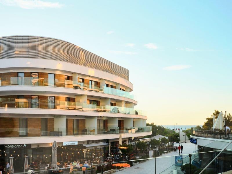 Hotel moderno con balconi curvi e area esterna al tramonto.