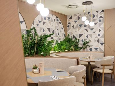 Moderner Hotel-Loungebereich mit runden Spiegeln, Pflanzen und beige Möbeln