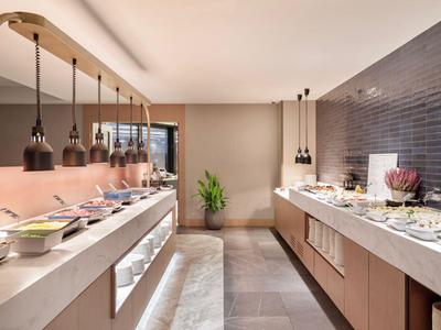 Moderner Buffetbereich mit warmem Licht, zwei Buffets und dekorativer Pflanze am Ende.