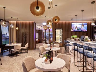 Modernes Café mit gemütlichen Sesseln, Tischen, Barhockern und warmem Licht.