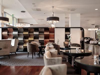 Eleganter Hotel-Loungebereich mit bequemen Sesseln und stilvollen Lampen an der Decke.