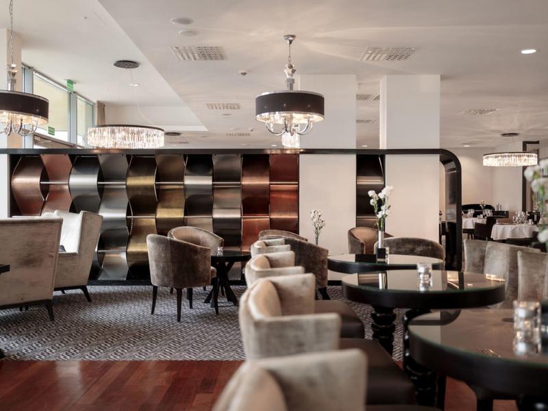 Elegancki salon z stylowymi fotelami i dekoracyjnymi przegrodami w ciepłych odcieniach.