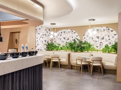 Modernes Restaurantinterieur mit heller Beleuchtung und Pflanzen an der Wand.