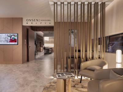 Moderner Hotel-Loungesitzbereich mit Sesseln, Teppich und Sichtschutz vor dem Eingangsbereich des Spabereichs.