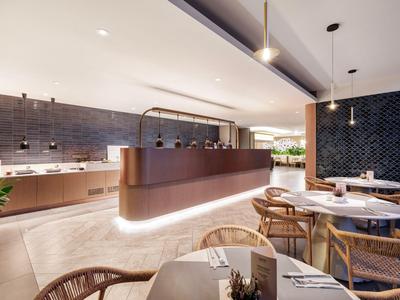 Moderner Essbereich mit runden Tischen, Holzstühlen und stilvoller Theke in warmem Licht.