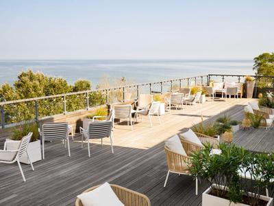Geräumige Dachterrasse mit Sitzgelegenheiten und Meerblick bei klarem Himmel.