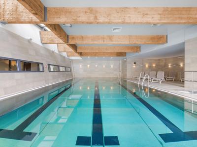 Moderner Innenpool mit Holzdeckenbalken und klar blauem Wasser in einem Hotel.