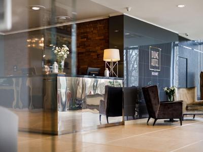 Moderner Hotel-Empfangsbereich mit glänzender Rezeption und Sitzbereich mit Sesseln.