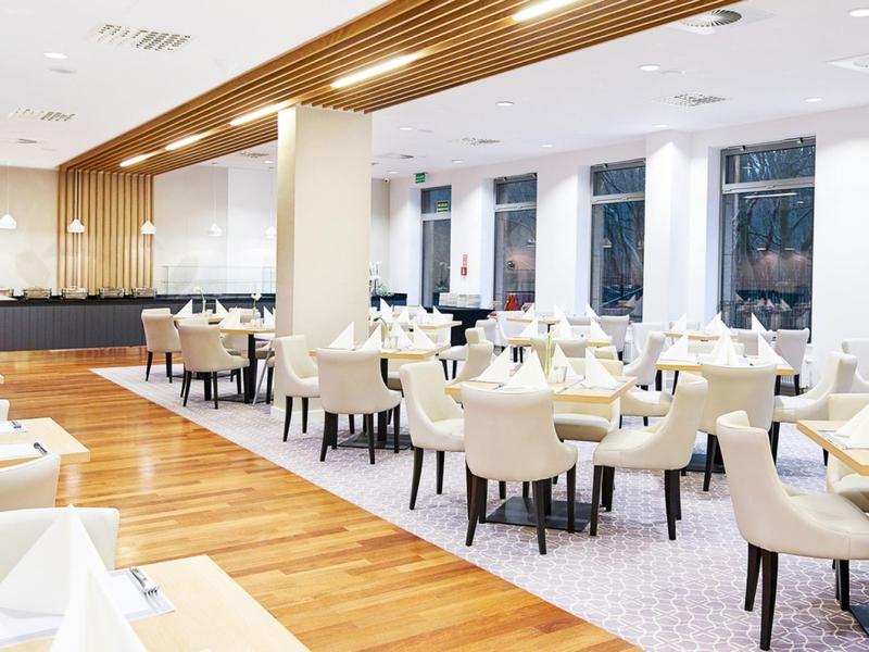 Sala da pranzo luminosa con sedie bianche e dettagli moderni in legno.