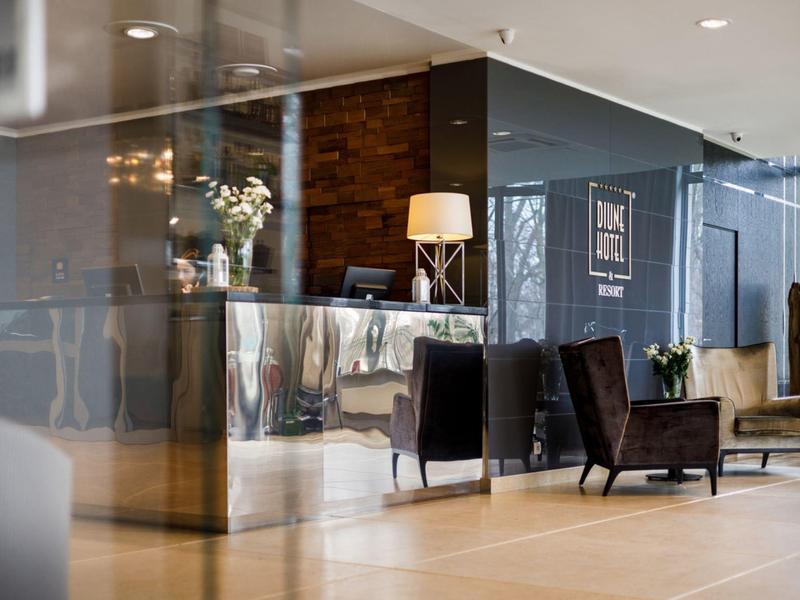 Area lobby moderna di un hotel con banco reception, poltrone e illuminazione d'atmosfera.