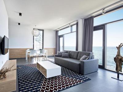 Modernes Wohnzimmer mit Sofa, Teppich und großen Fenstern mit Meerblick