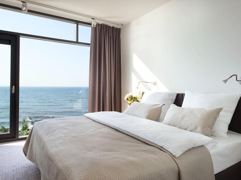 Chambre d'hôtel lumineuse avec grand lit et vue sur la mer par une fenêtre