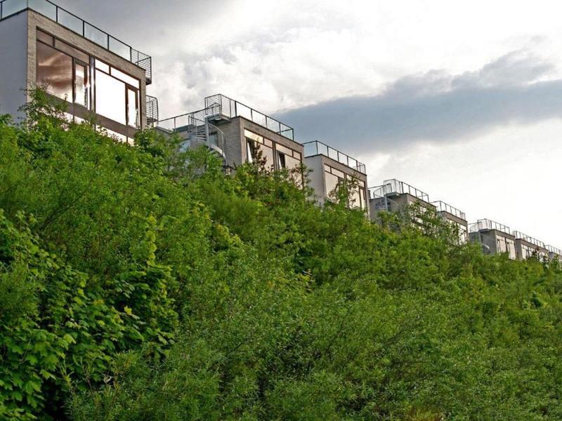 Des bâtiments modernes sont élevés derrière une végétation dense par une journée nuageuse.