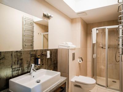 Modernes Badezimmer mit Waschbecken, Spiegel, Toilette und Dusche in einem Hotel.
