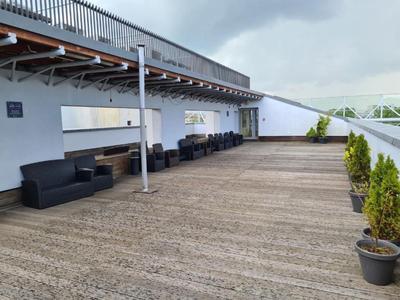 Ampia terrazza con pavimento in legno, divani e tavoli sotto un cielo nuvoloso all'hotel.