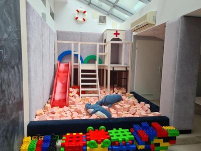 Bambini che giocano al chiuso con struttura per arrampicata, scivolo e blocchi di schiuma.