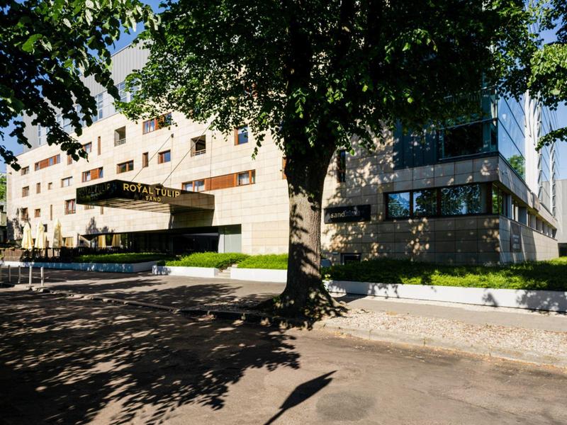 Edificio di hotel moderno con facciata bianca circondato da alberi e ombre.