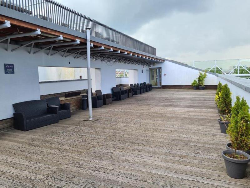 Ampia terrazza con pavimento in legno, divani e tavoli sotto un cielo nuvoloso all'hotel.