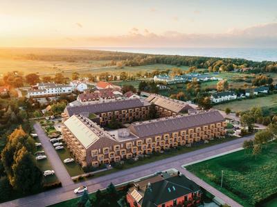 Sonnenuntergang über einem großen Hotelkomplex in ländlicher Umgebung mit Straßen und Grünflächen.