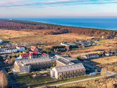 Luftaufnahme eines Hotels an der Küste mit umliegender Landschaft und Meer im Hintergrund.