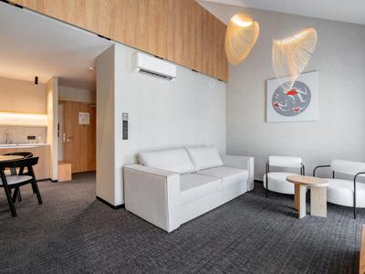 Modern eingerichteter Hotel-Wohnbereich mit Sofa, Sesseln und einem kleinen Holztisch.