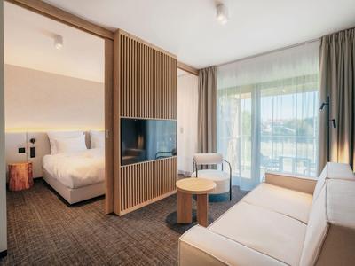 Modernes Hotelzimmer mit gemütlichem Sofa, Fernseher und Balkon mit Ausblick.