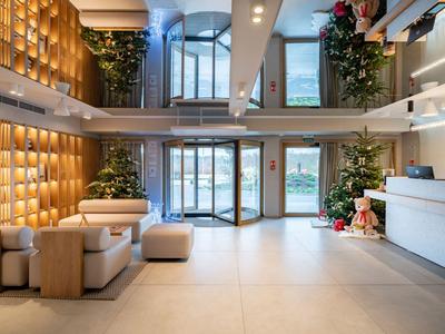 Helles und modernes Hotelfoyer mit Sitzbereich, Pflanzen und großen Glasfenstern.