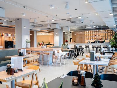 Modern eingerichteter Hotel-Speisesaal mit hellen Holzstühlen und gedeckten Tischen.