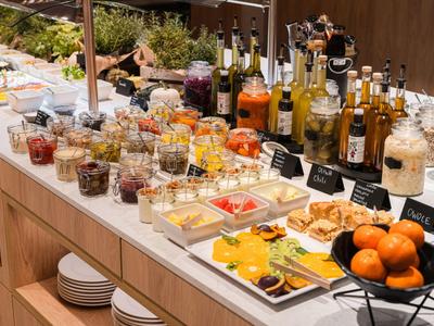 Buffet mit vielfältigen Speisen und Getränken, darunter Obst, Gebäck und Säfte.