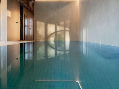 Innenpool mit blauem Wasser und Schatten an der Wand in einem Hotel