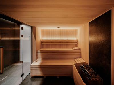 Moderne Sauna mit mehrstufigen Holzliegen und warmem Licht im Hotelinterieur.