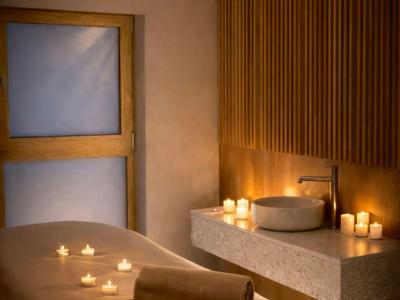 Gemütlicher Wellnessraum mit Massageliege, Handtüchern und Kerzenbeleuchtung.